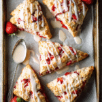 homemade strawberry scones cooling on a baking sheet lined with parchment paper