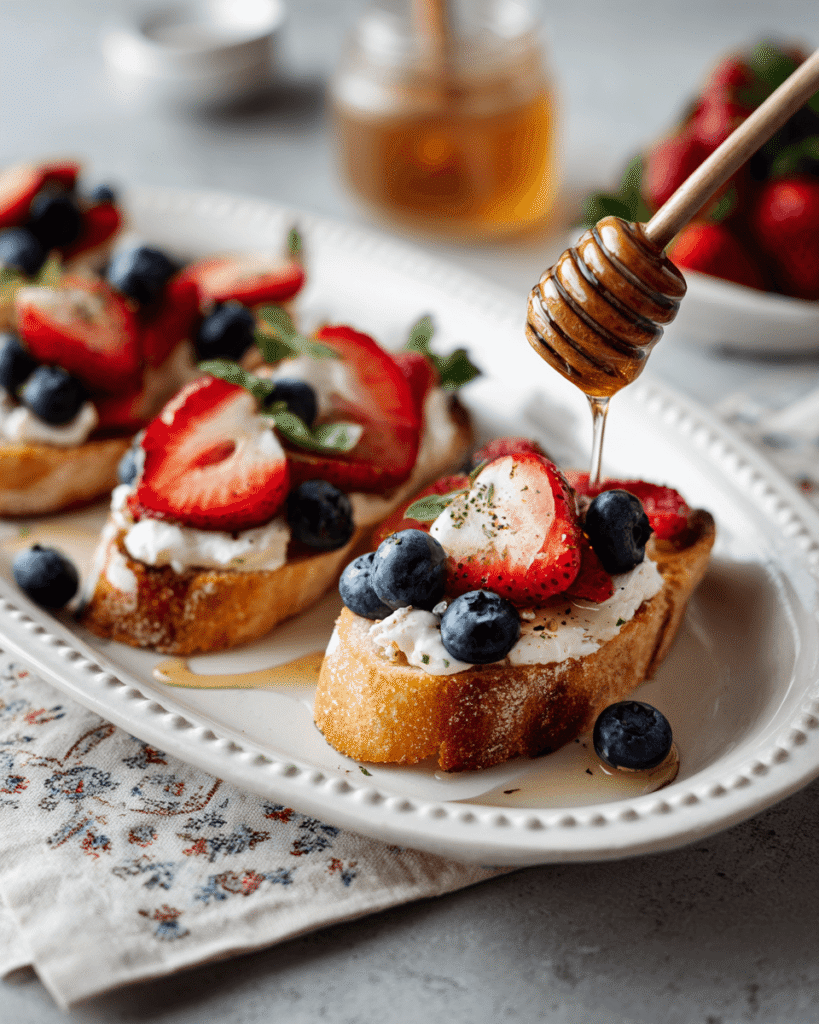 Strawberry and blueberry bruschetta arranged on a serving platter with fresh mint leaves